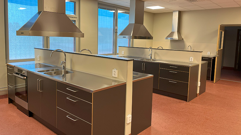 Hemkunskapssal med flera köksbänkar.